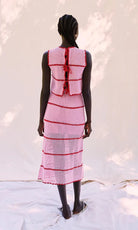 Person wearing a pink dress with red accents against a white background