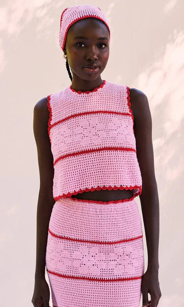 Model wearing a pink and red crochet outfit against a white background