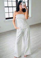 Woman wearing a strapless polka dot jumpsuit in a minimalistic room.