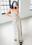 Woman wearing a strapless polka dot dress in a minimalistic room.