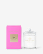 A clear glass jar candle with white wax and a matching clear glass lid sits beside a bright pink rectangular box with a gold label. The product is branded GLASSHOUSE COPENHAGEN, and the scent appears to be Rosemary.