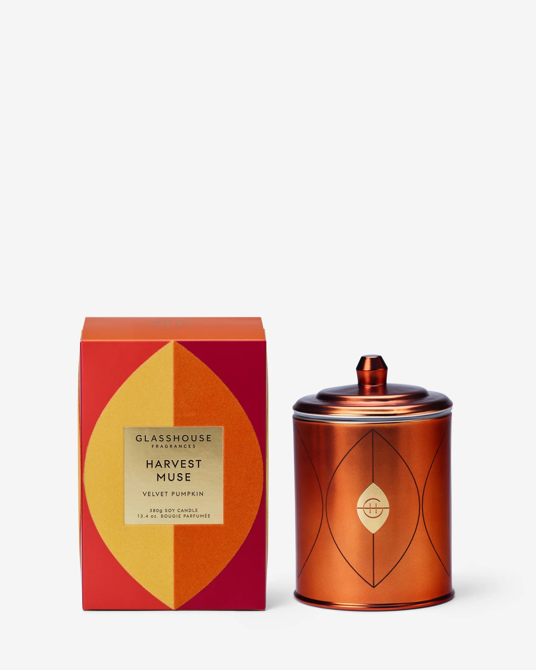 A copper-colored metal tin candle with a lid sits next to its red and yellow packaging box on a clean white background. The box features the brand name 'GLASSHOUSE CANDYSCENTS' and the scent 'HARVEST MUSE'.