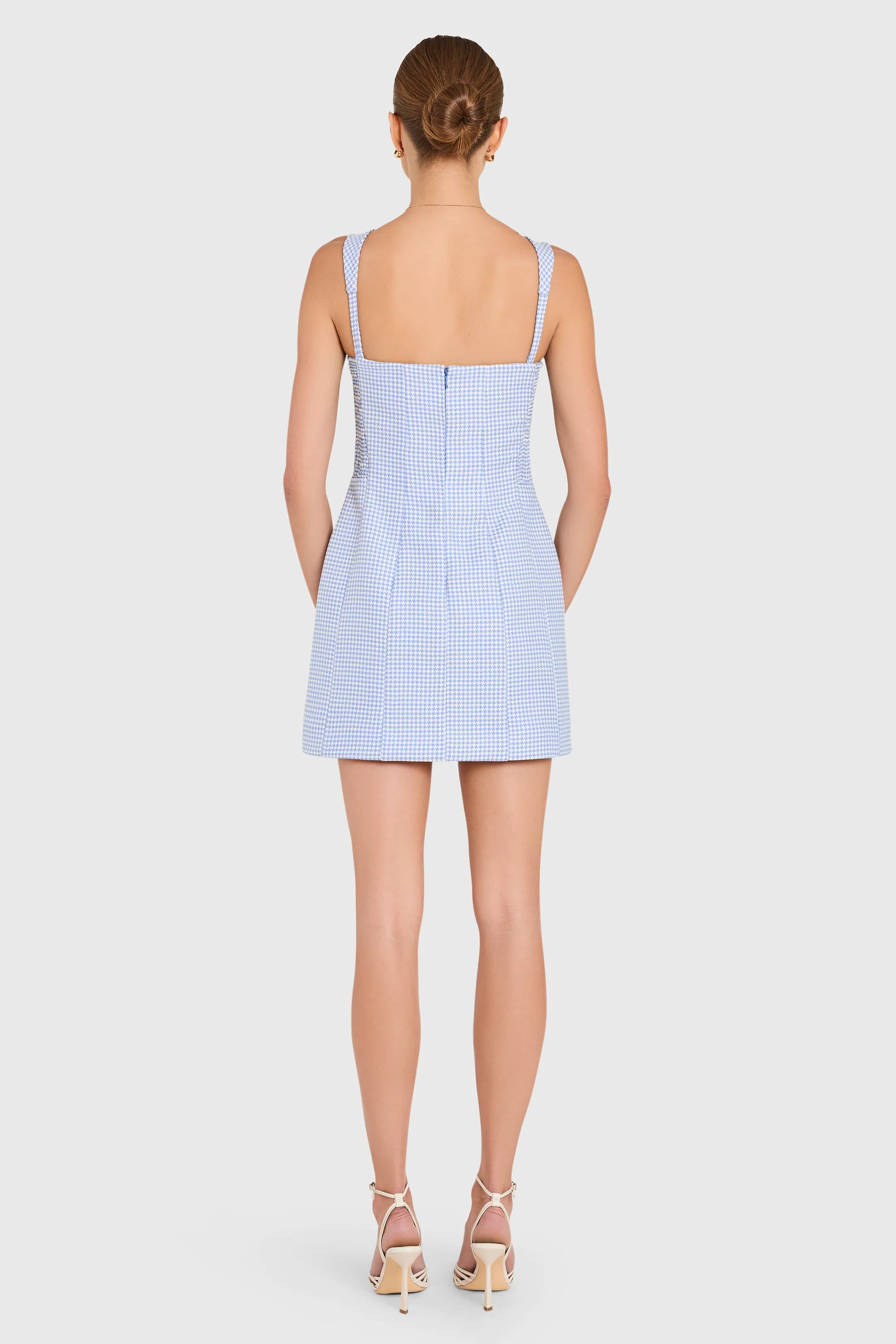 Woman wearing a light blue checkered dress on a white background