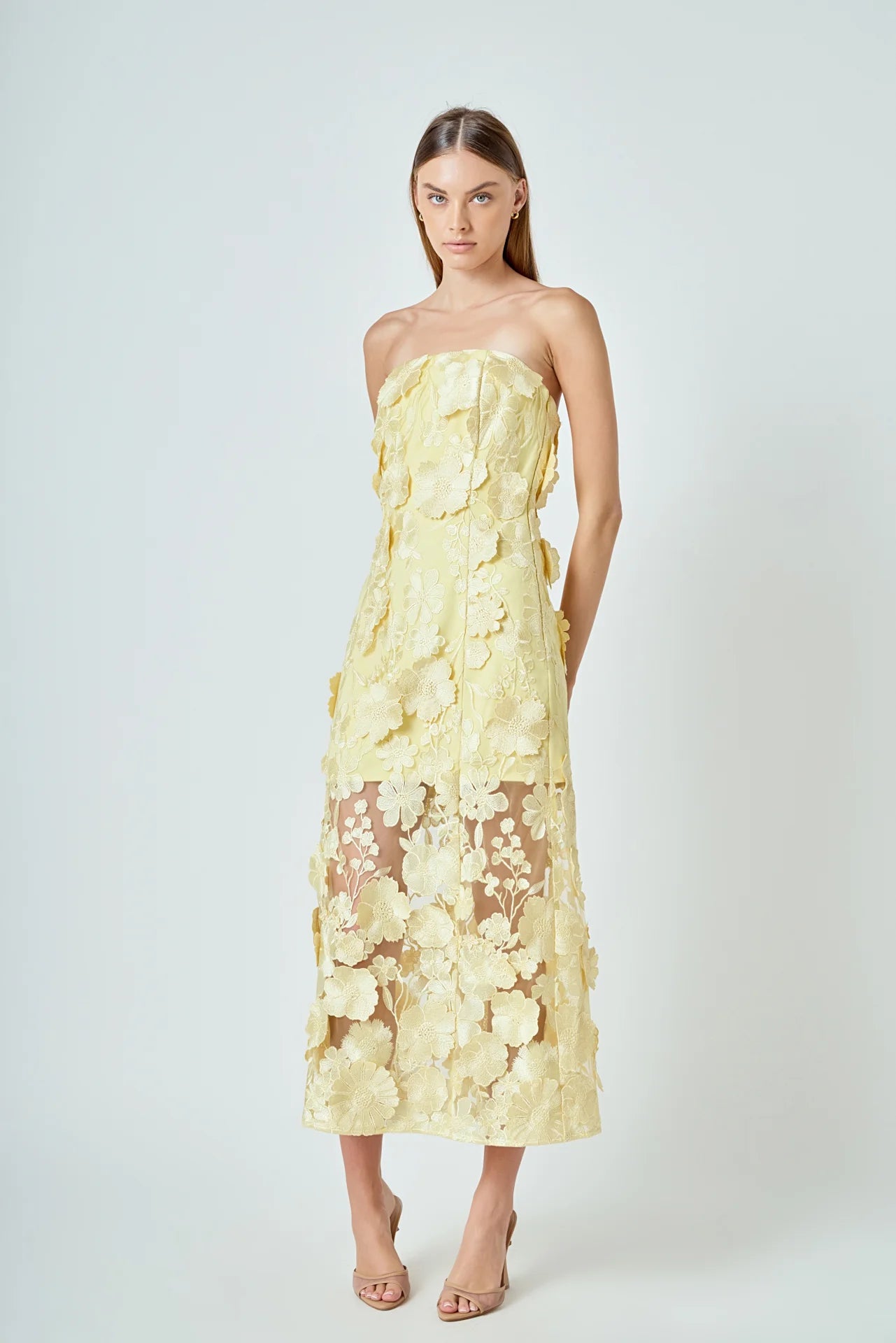 Woman wearing a strapless yellow floral dress on a white background