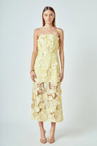 Woman wearing a strapless yellow floral dress on a white background