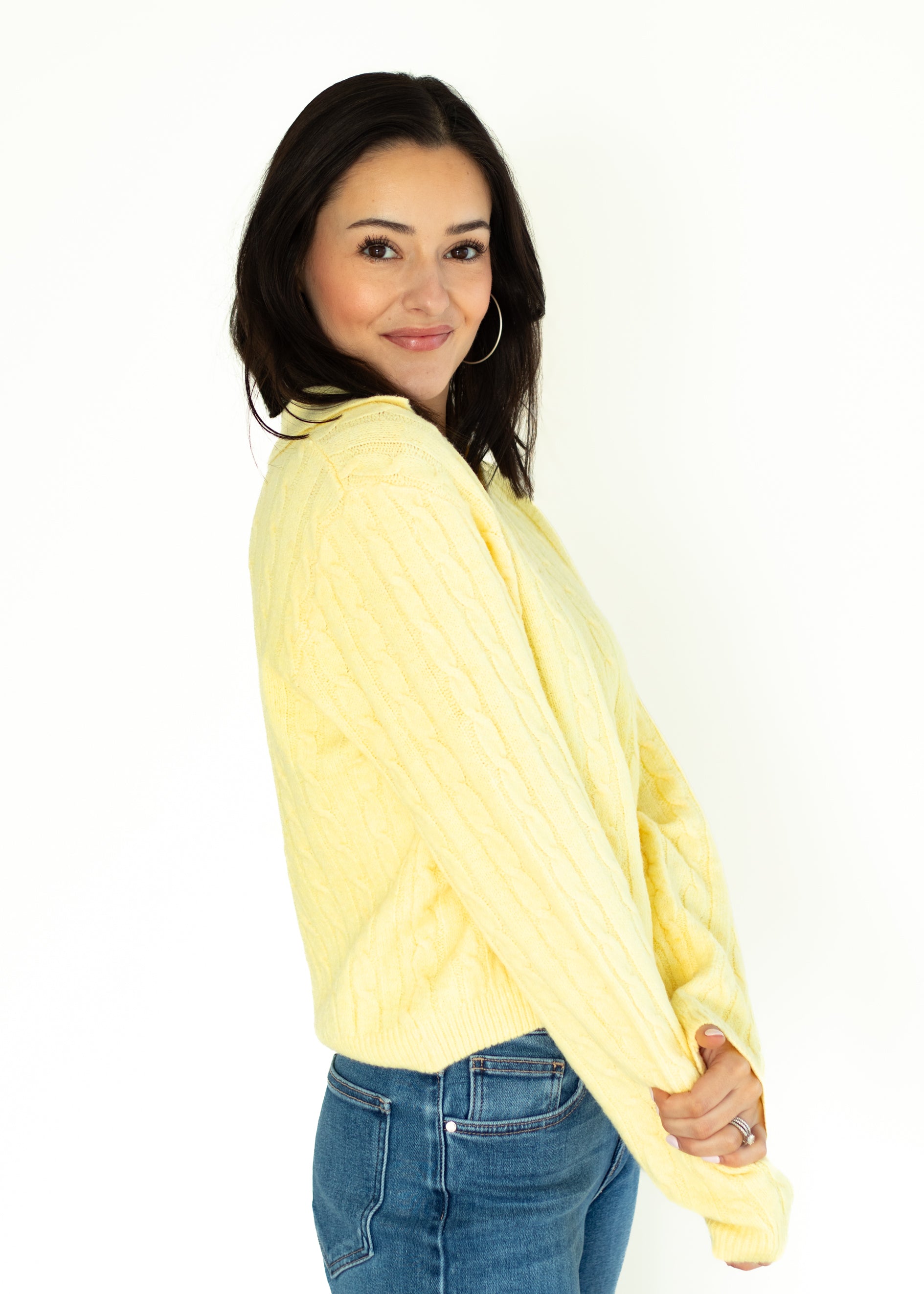 Woman wearing a yellow sweater and blue jeans on a white background