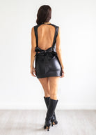 Woman wearing a black leather set with a bow detail on a white background