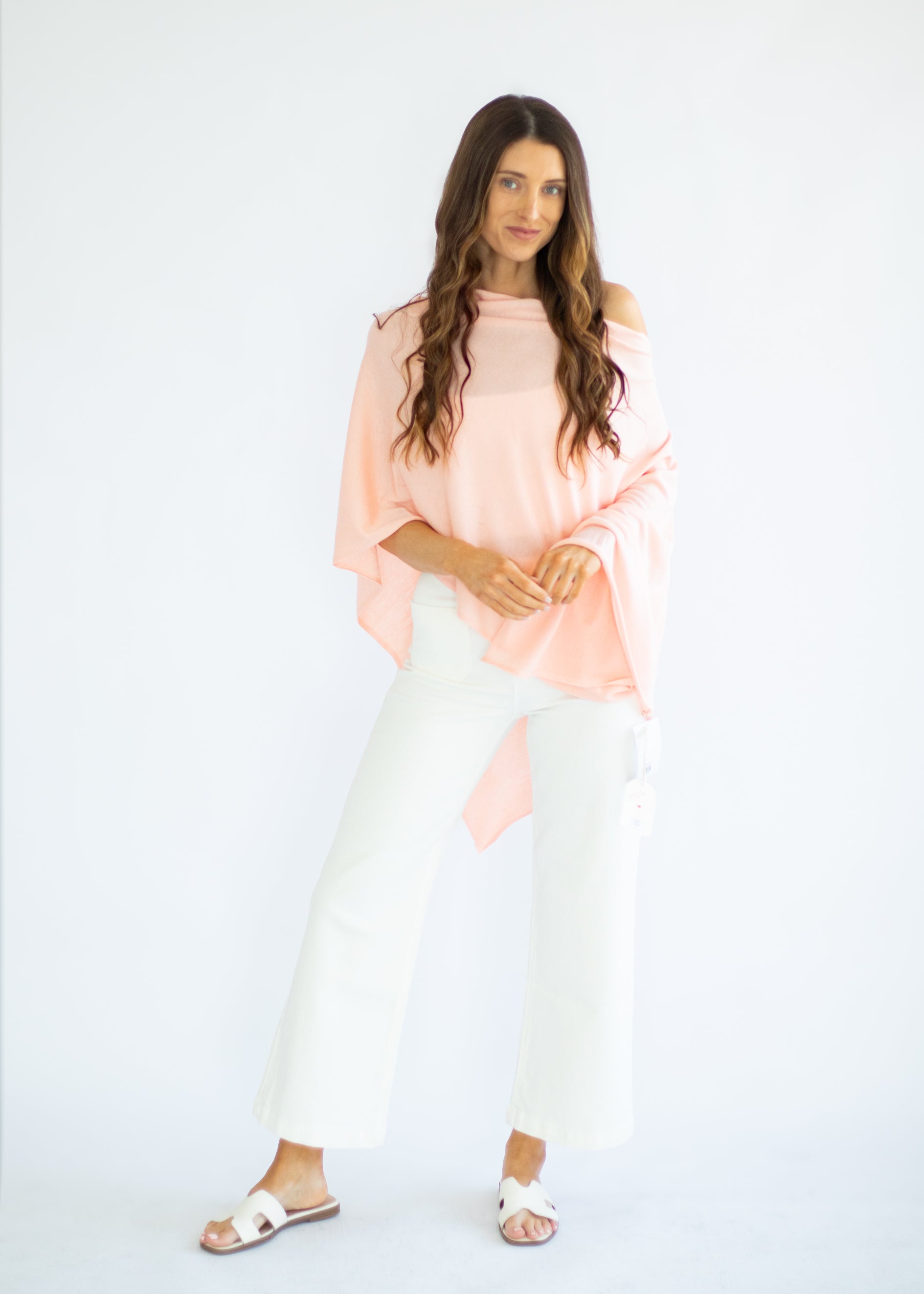 Woman wearing a peach top and white pants on a white background
