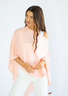 Woman wearing a light pink off-shoulder top against a white background