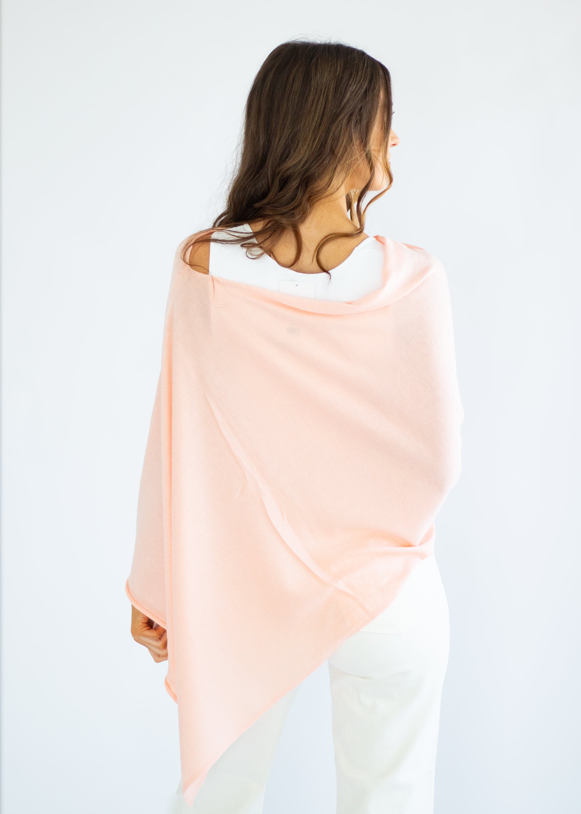 Woman wearing a pastel pink and green gradient shawl on a white background
