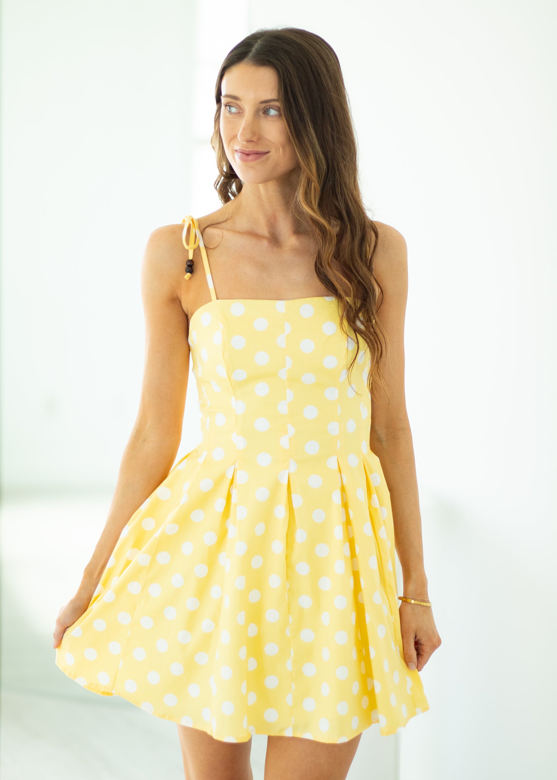 Woman wearing a yellow polka dot dress against a white background