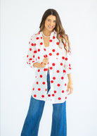 Woman wearing a white shirt with red polka dots and blue jeans on a white background