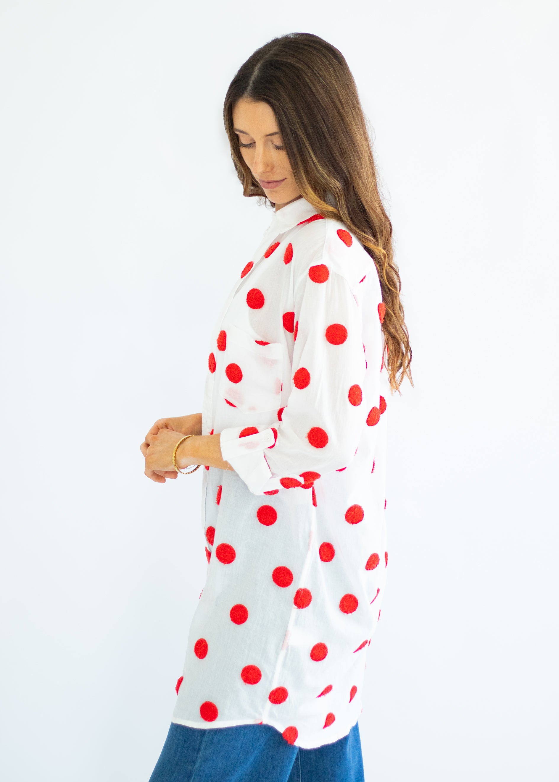 Woman wearing a white blouse with red polka dots on a white background