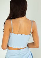 Light blue scalloped top worn by a person on a plain background