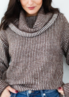 Woman wearing a brown and white striped sweater with a cowl neck.