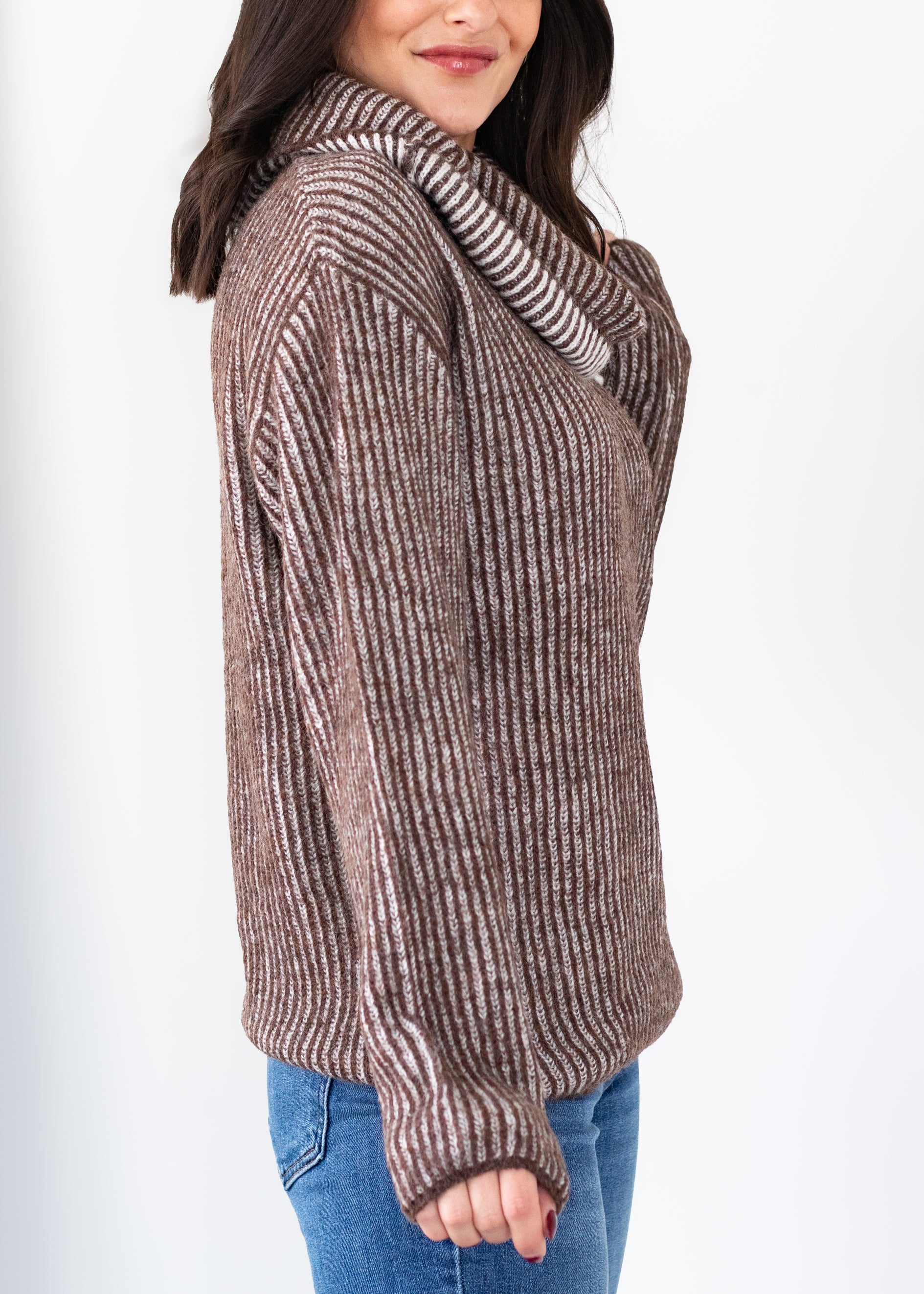 Woman wearing a brown ribbed sweater with a white background