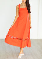 Woman wearing an orange dress with lace details on a plain background