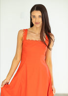 Woman wearing an orange dress against a white background