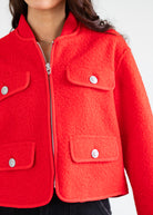 Close-up of a red jacket with silver buttons on a white background