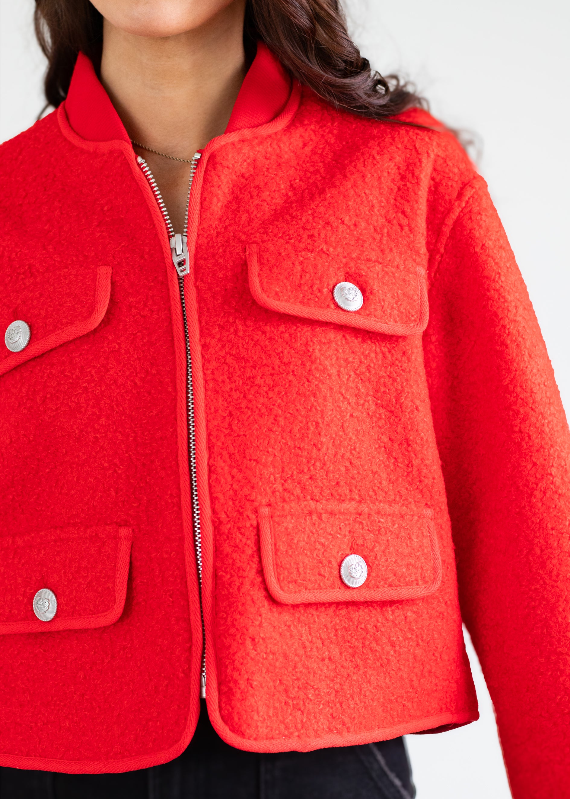 Close-up of a red jacket with silver buttons on a white background