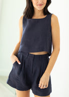 Woman wearing a navy sleeveless top and shorts on a white background