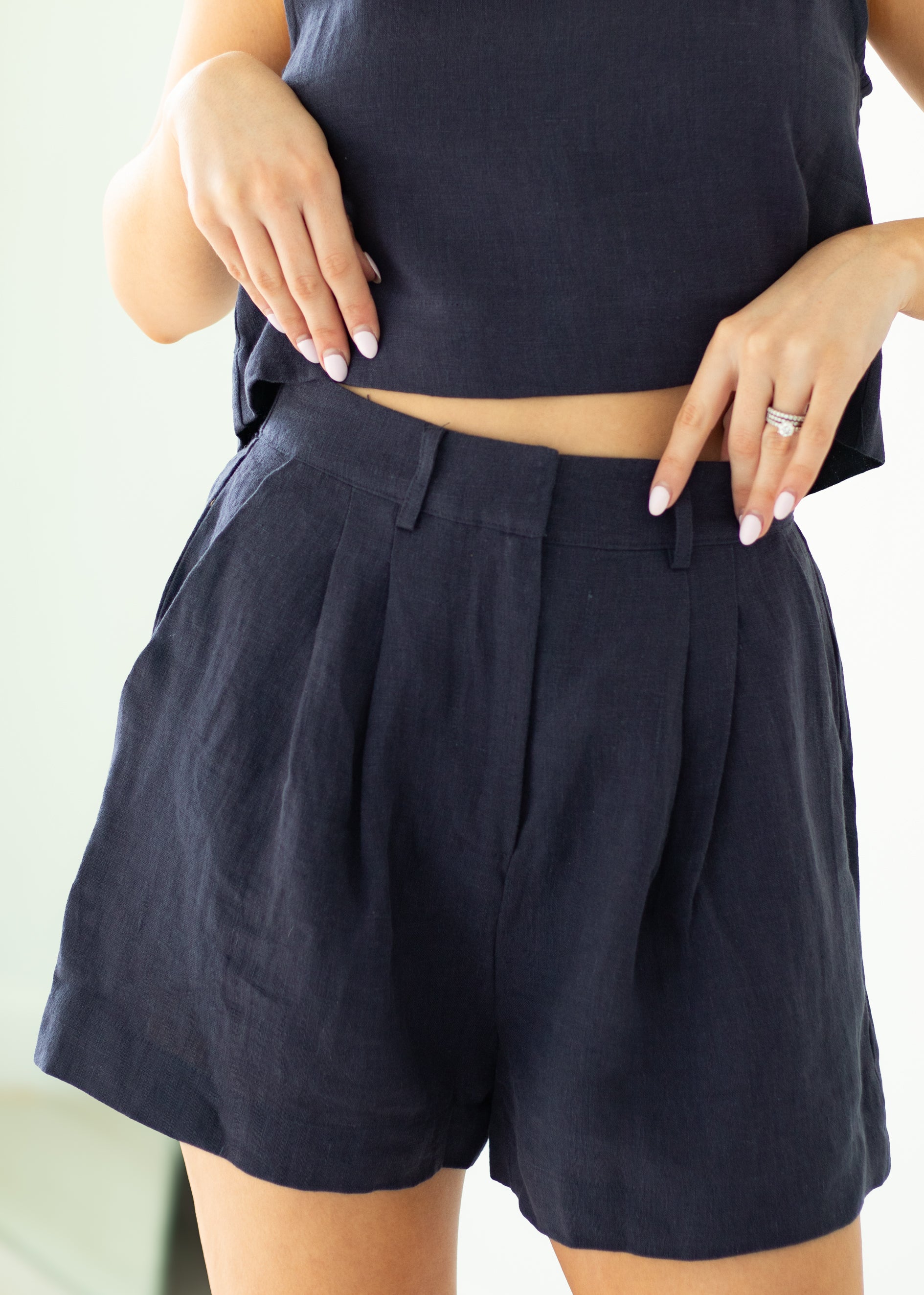 Person wearing navy shorts and a matching top against a light background