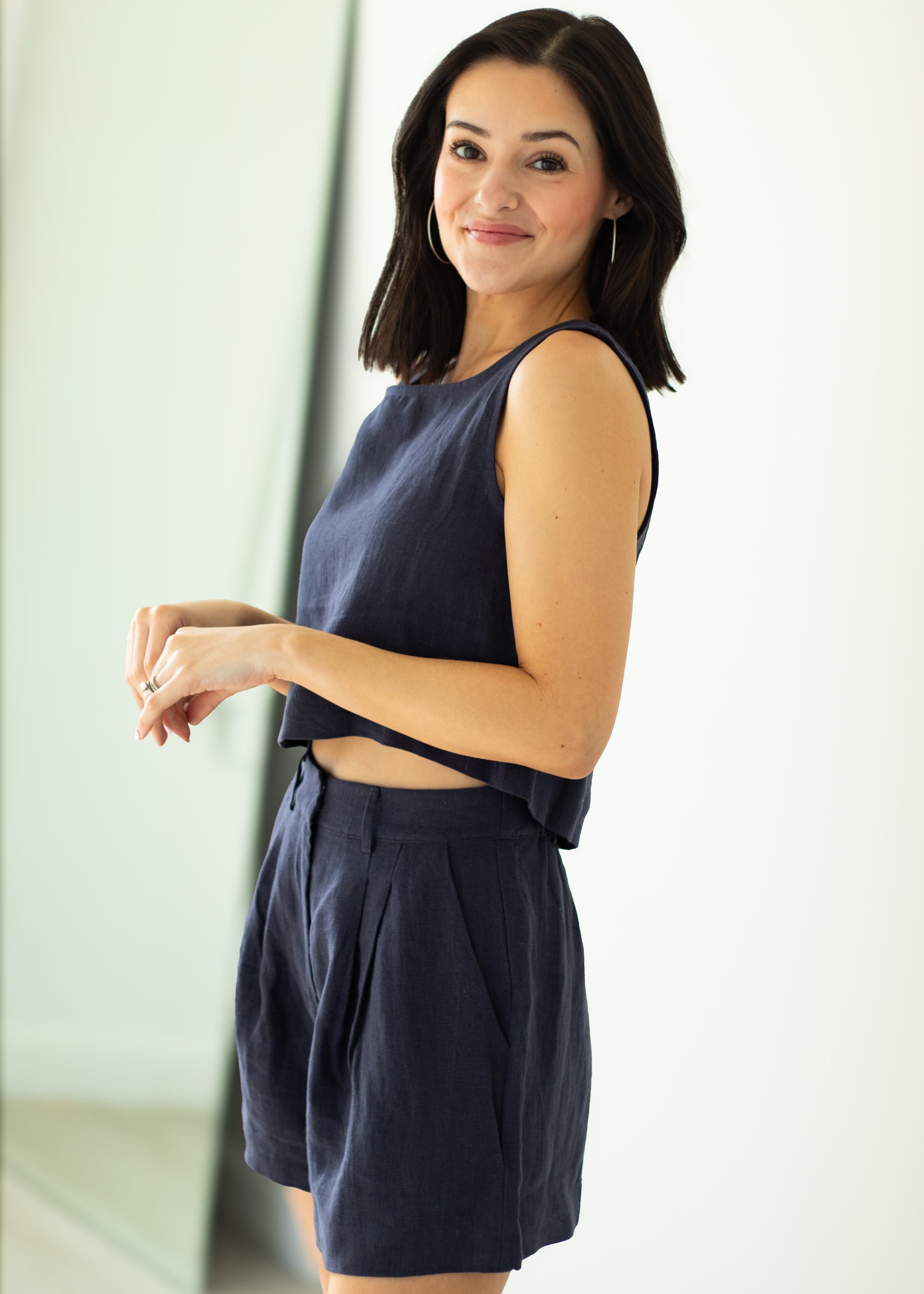 Woman wearing a navy sleeveless top and shorts against a white background