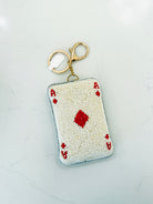 A small card-shaped keychain or pouch designed to look like an Ace of Spades playing card, made with white and red seed beads and finished with a gold-tone split ring and clasp, shown on a light marble surface.