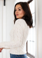 Woman wearing a white cable knit sweater indoors