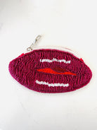 A small zippered pouch shaped like a pair of lips, covered in dark magenta and pink beaded texture with white bead details for the teeth and a red bead accent for the lips, shown on a white background.
