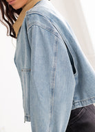 Light blue denim jacket worn by a person on a white background