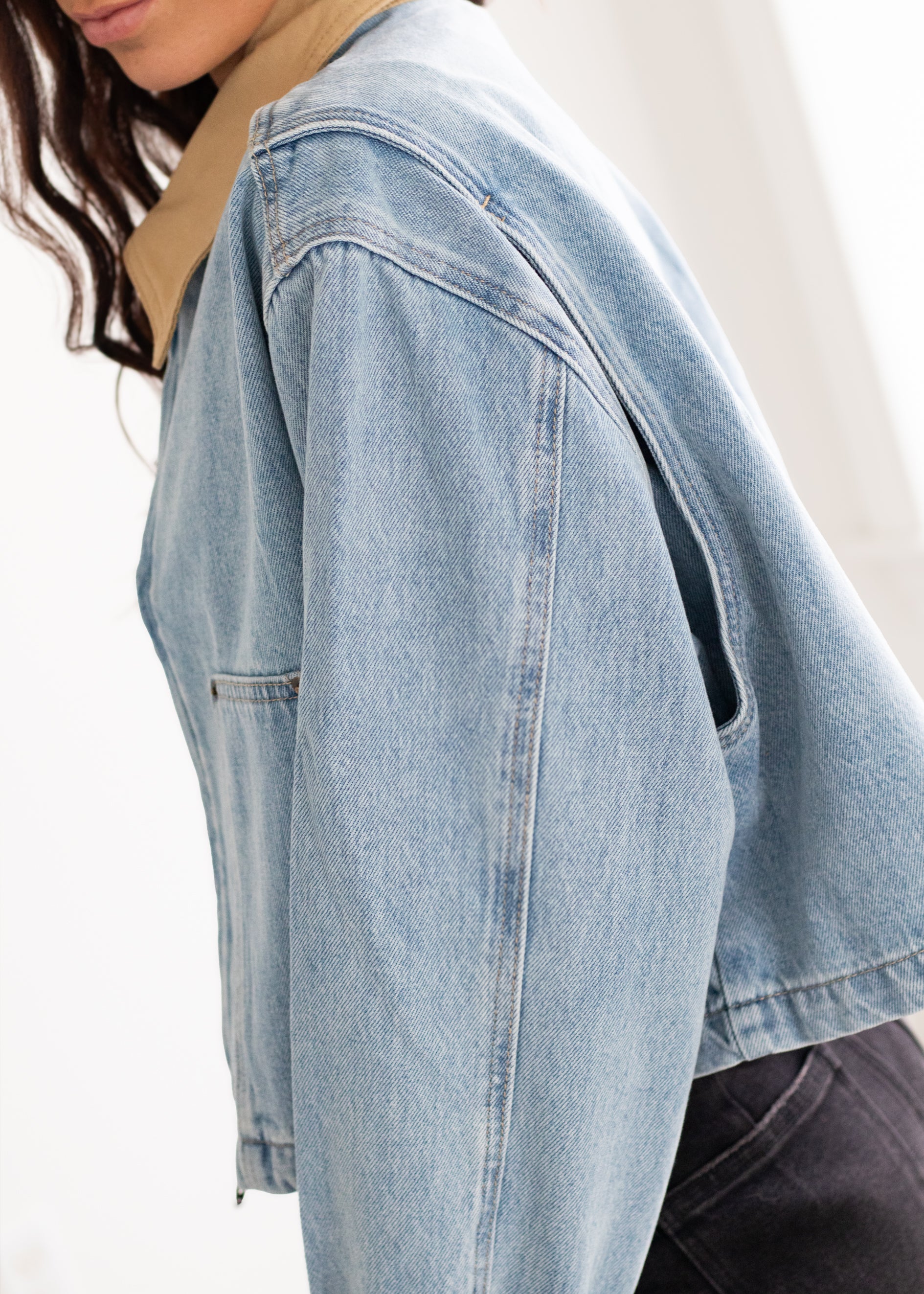 Light blue denim jacket worn by a person on a white background
