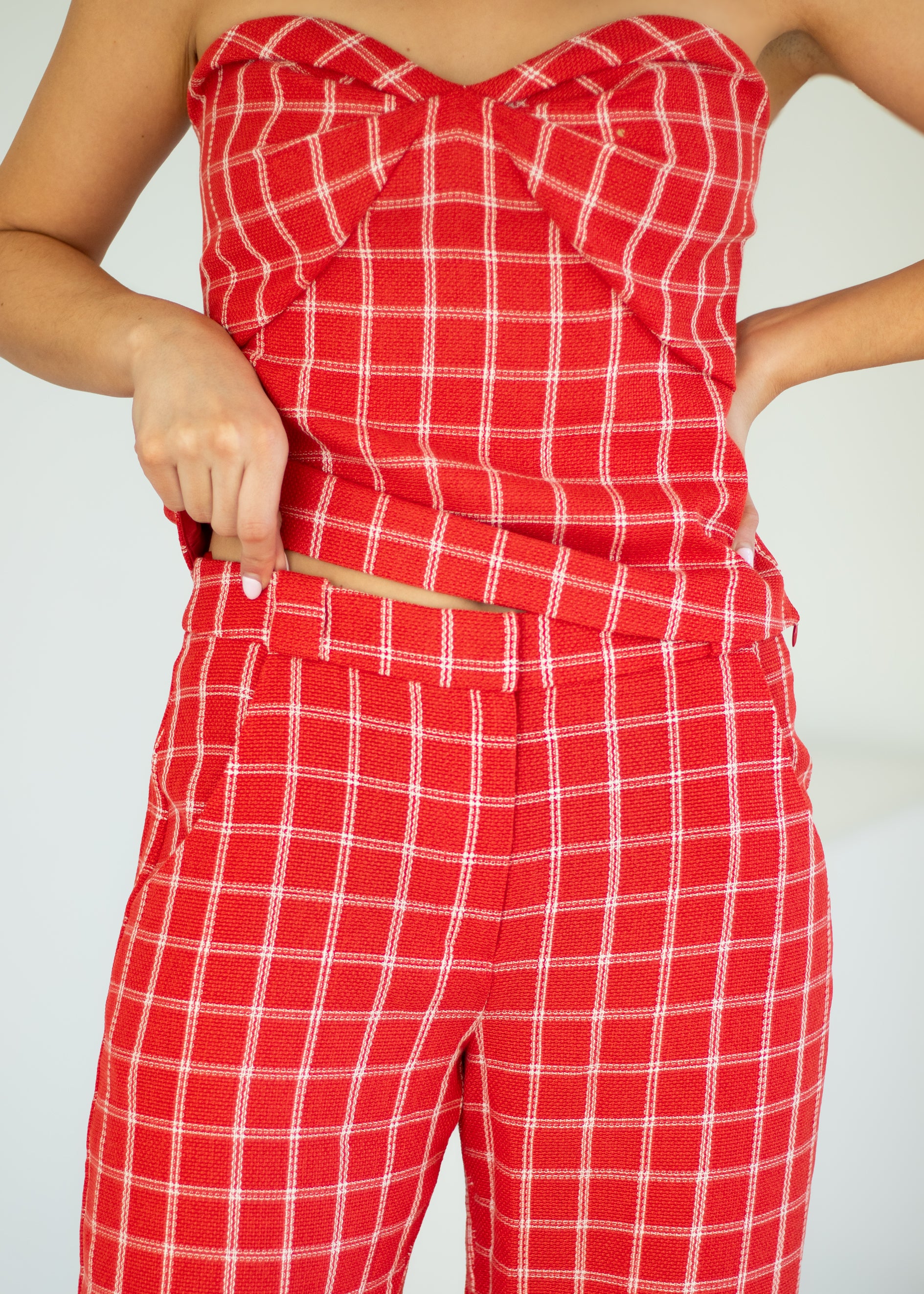 Red plaid jumpsuit worn by a person on a light gray background