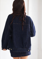 Person wearing a dark denim jacket on a white background