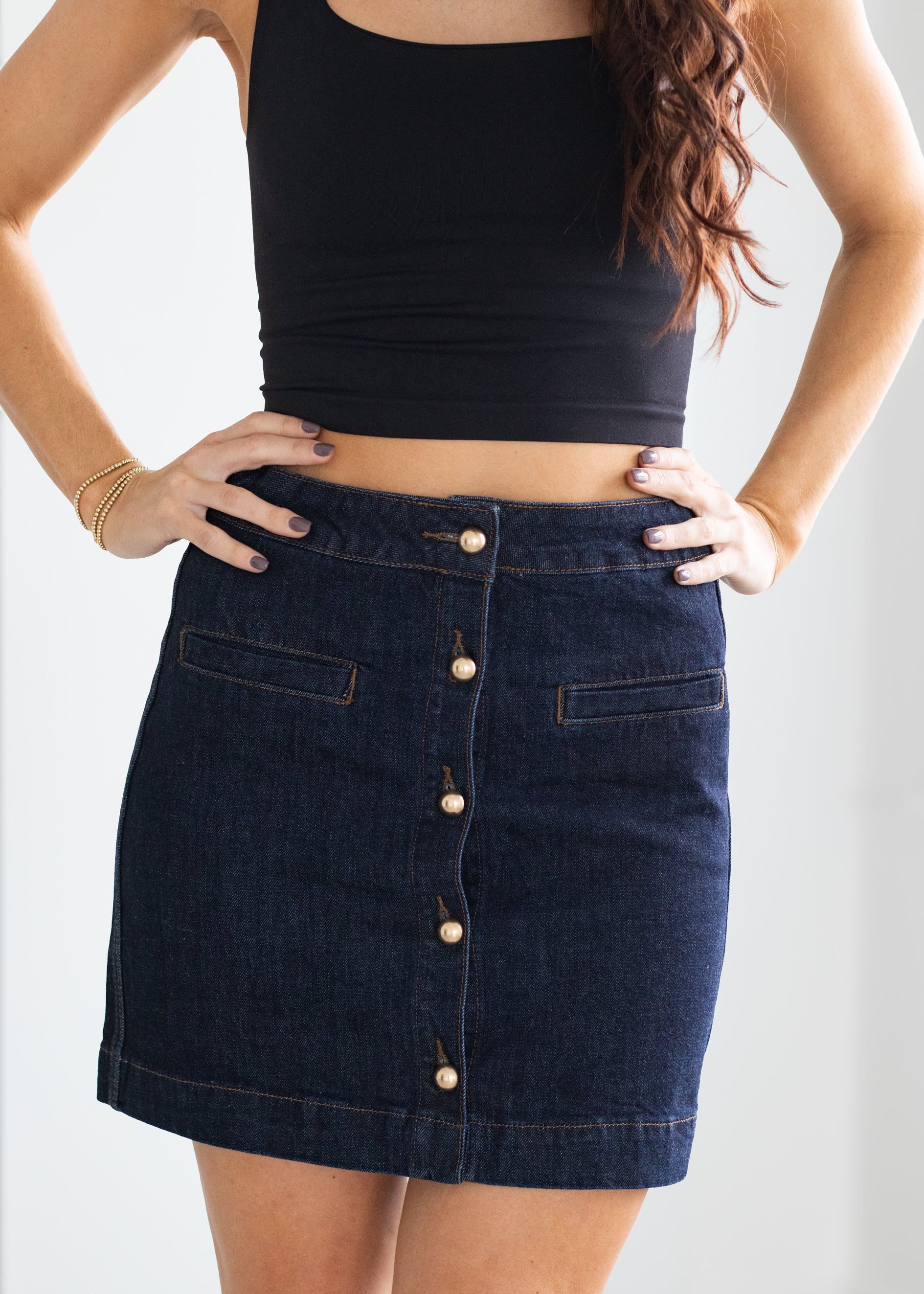 Person wearing a black crop top and denim skirt on a plain background