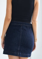 Person wearing a dark blue denim skirt on a white background