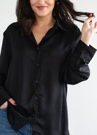 Woman wearing a black button-up shirt against a white background