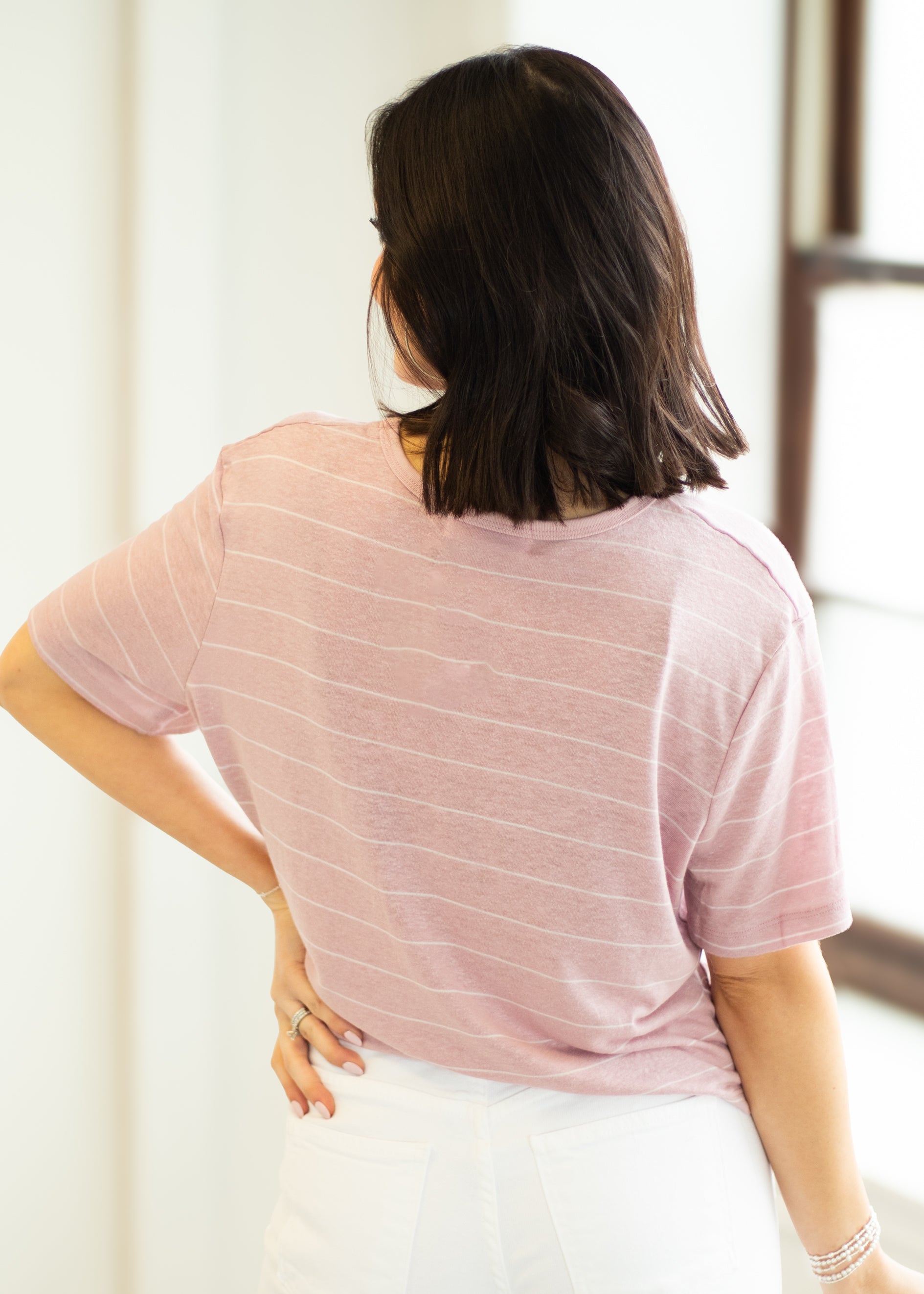 Person wearing a pink striped shirt in a minimal indoor setting