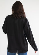 Person wearing a black blouse with long sleeves on a white background