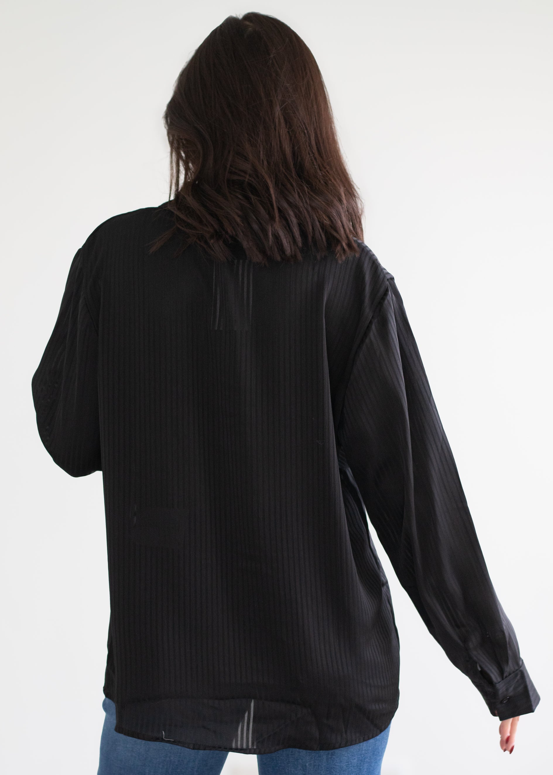 Person wearing a black blouse with long sleeves on a white background