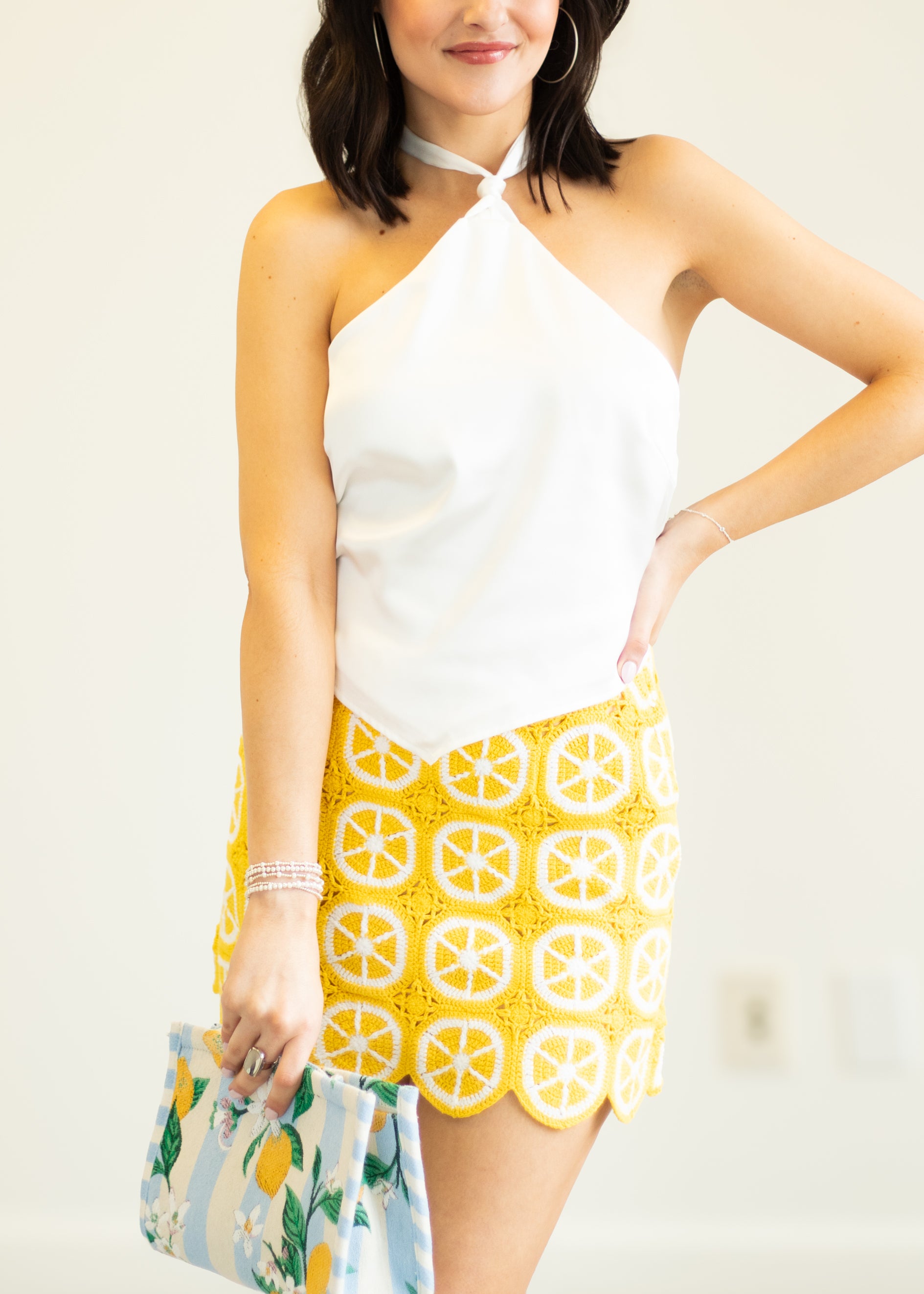 Woman wearing a white top and yellow patterned skirt with a white background