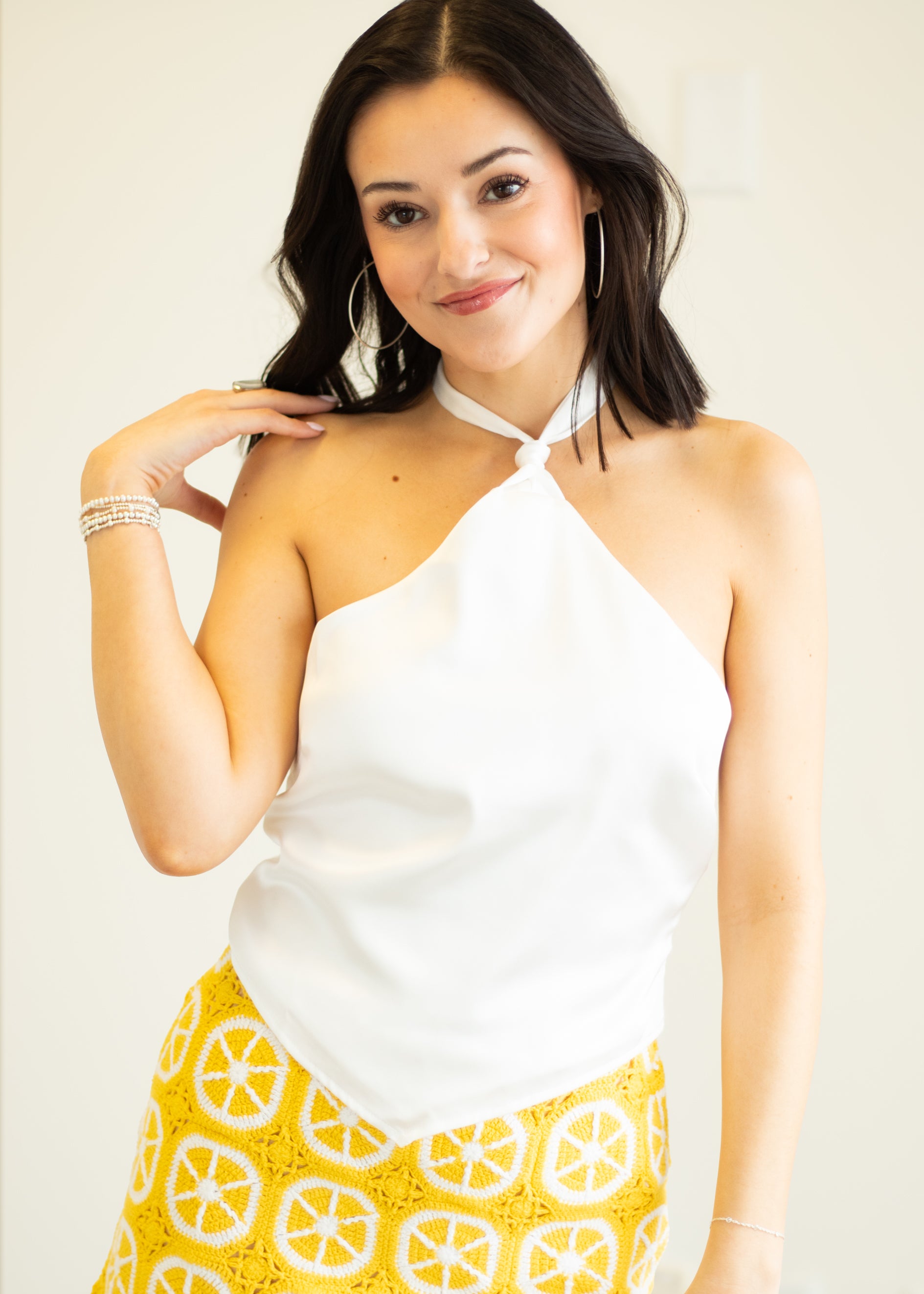 Woman wearing a white top and yellow patterned skirt against a plain background