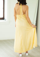 Woman wearing a yellow dress with thin straps in a minimal indoor setting