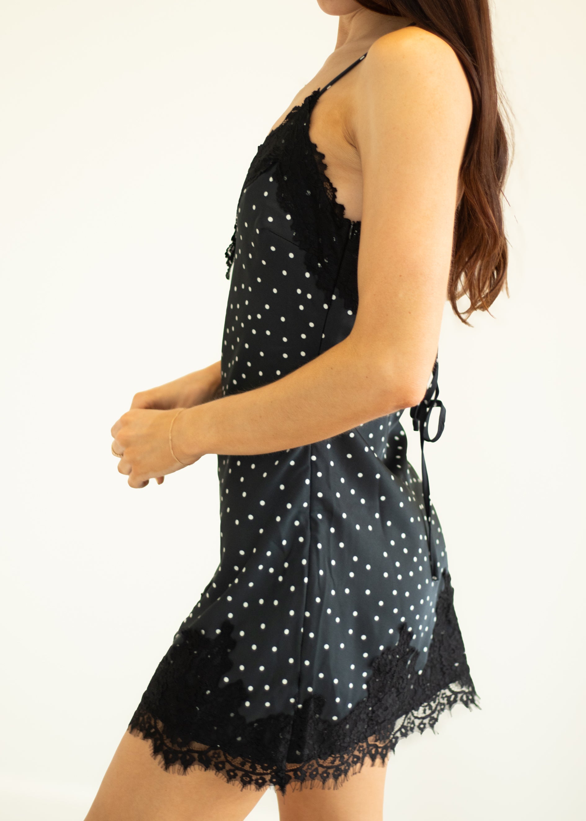 Black polka dot dress with lace trim on a white background