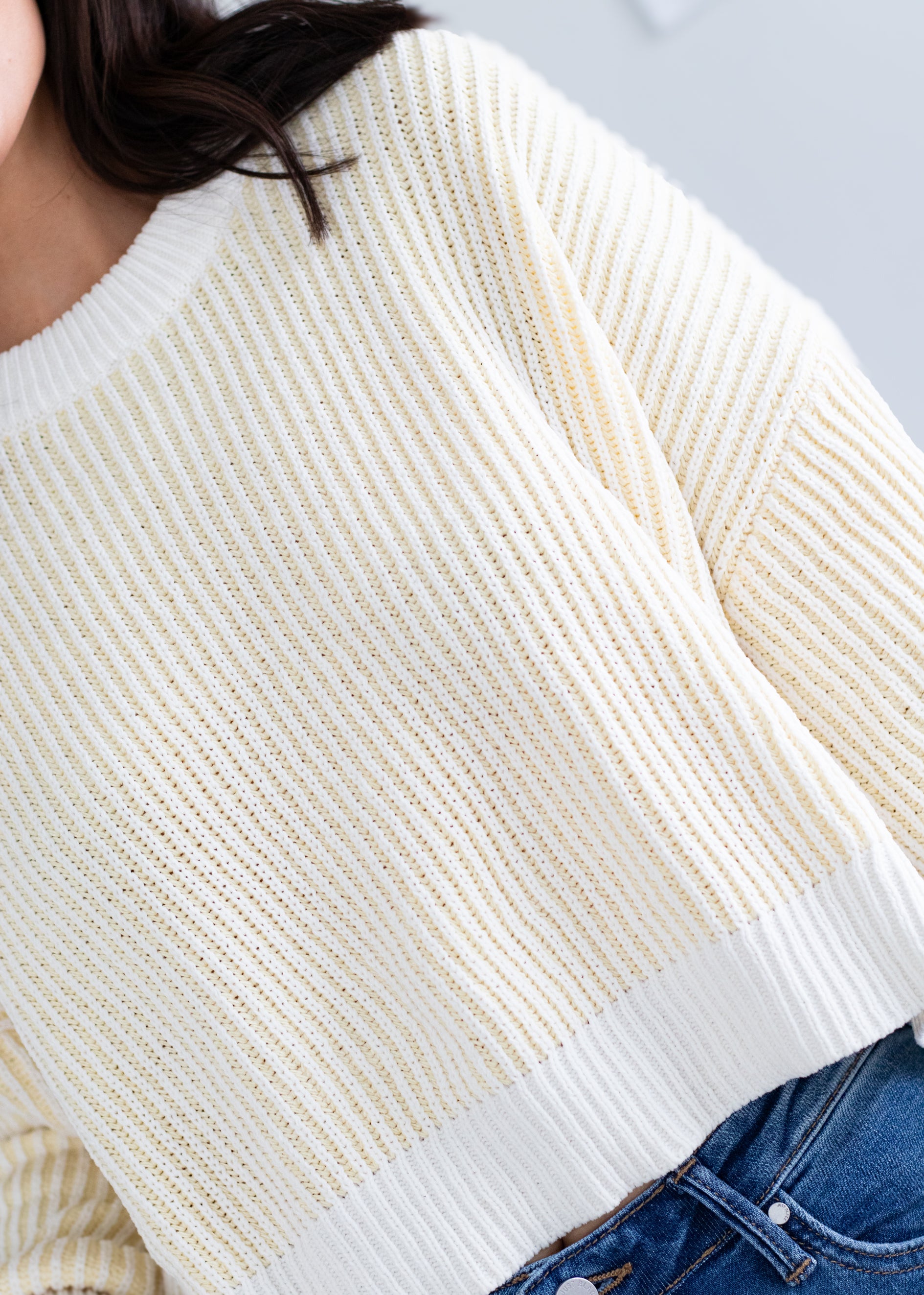 Close-up of a person wearing a white and yellow striped sweater with a blurred background