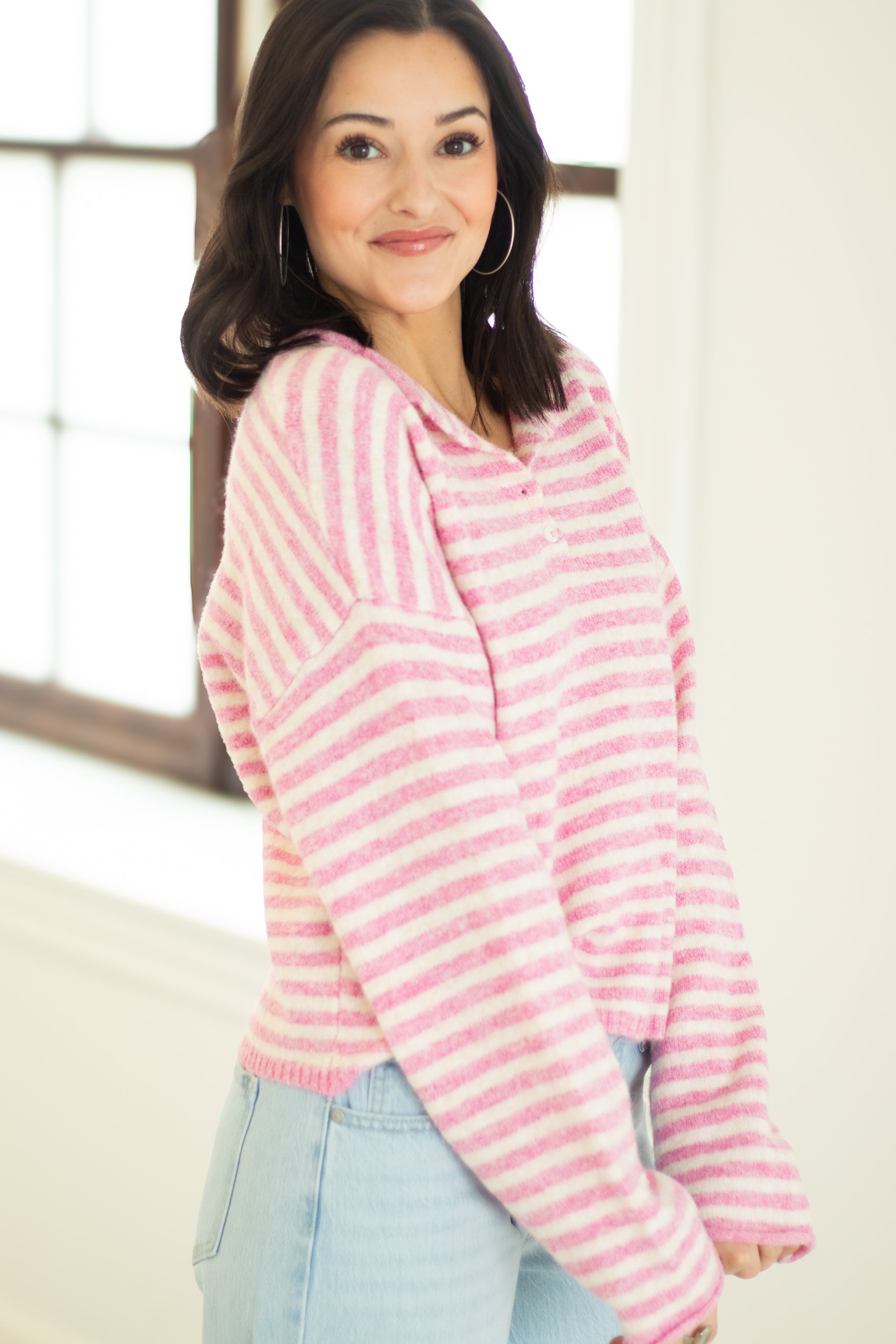 Woman wearing a pink and white striped sweater indoors