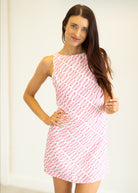 Woman wearing a pink and white patterned dress against a plain background