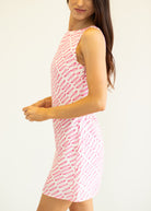 Woman wearing a pink and white patterned dress against a plain background