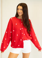 Woman wearing a red sweater with white star patterns on a plain background