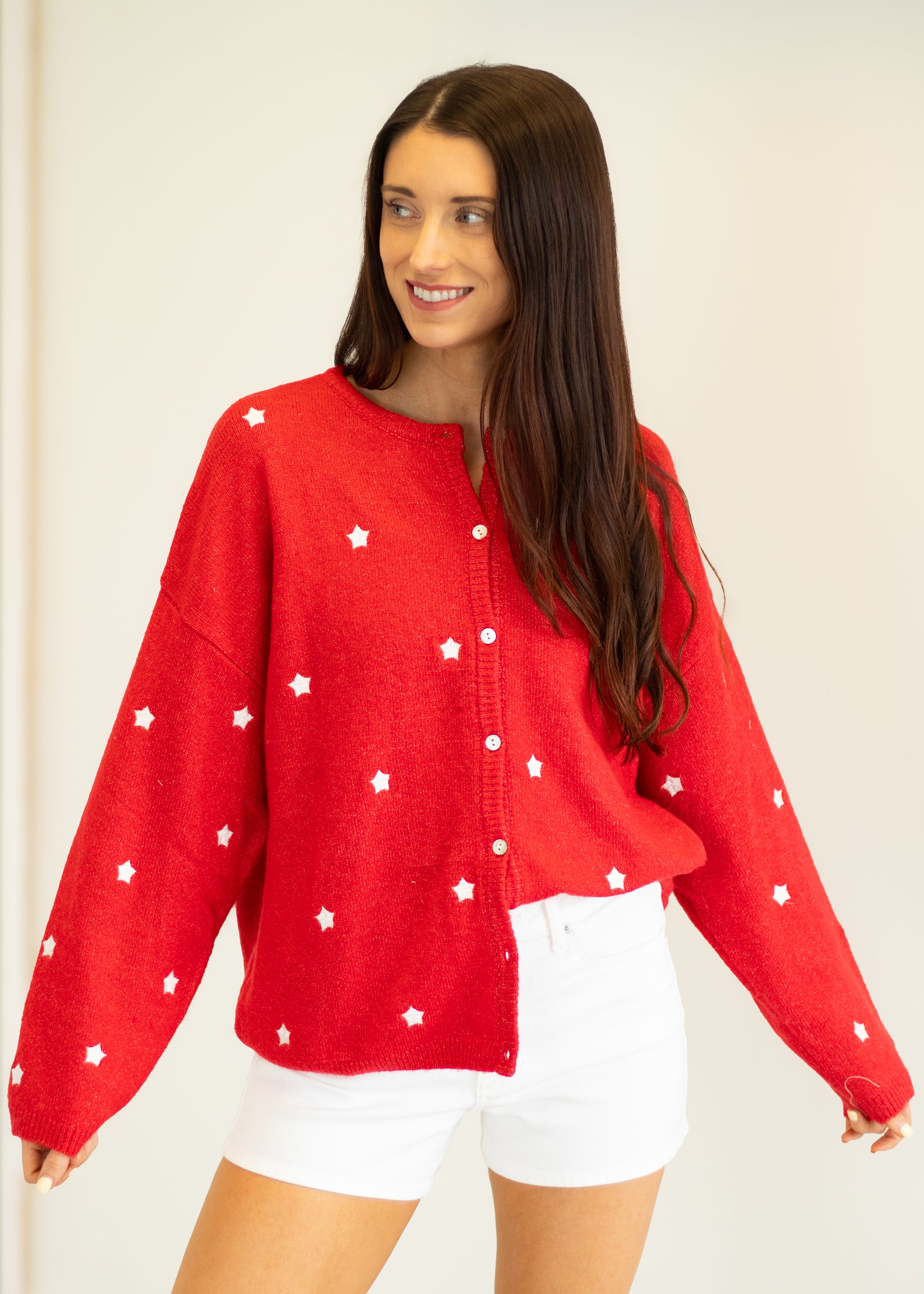 Woman wearing a red sweater with white star patterns on a plain background
